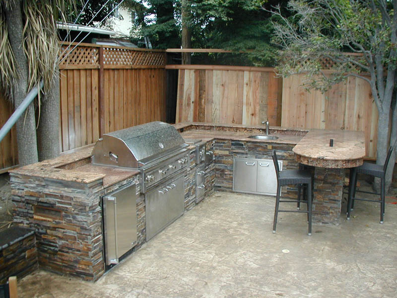 Outdoor kitchen with stone counters and patio seating, representing hardscape design services in Campbell and the South Bay.